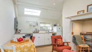 A compact living space with a dining area, kitchen, and seating area. - Ffrwd Cottage (Bodorgan)