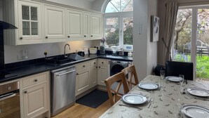 Ett modernt kök med vita skåp, en svart bänkskiva och en matplats med plats för sex personer, komplett med tallrikar och glas.