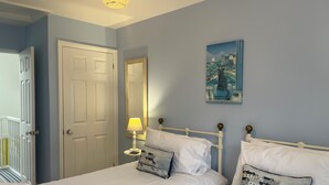 Une chambre avec deux lits, une porte, un miroir et un tableau au mur.