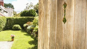A wooden door with a metal handle and a decorative glass window. - Maes y Cregyn (Marianglas)