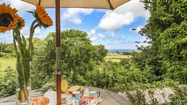 An outdoor dining table with a view of a green landscape and the sea. - Maes y Cregyn (Marianglas)