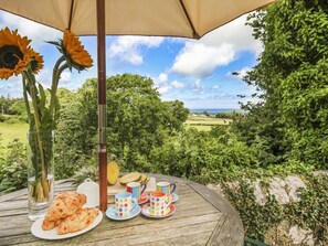 An outdoor dining table with a view of a green landscape and the sea. - Maes y Cregyn (Marianglas)