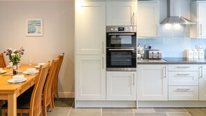 A modern kitchen with white cabinets, a built-in oven, and a toaster. - Exmoor View (South Molton)
