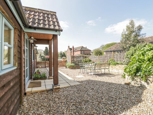 A wooden house with a tiled roof, a gravel patio, and a wooden fence. - Shippon Barn (Yeovil)