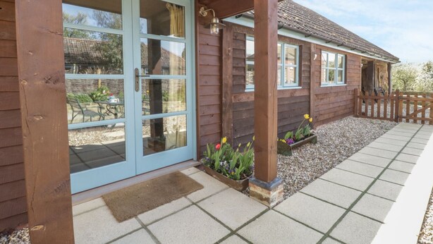 Une maison en bois dotée d’un porche couvert, d’une porte-fenêtre coulissante et d’un chemin de gravier.