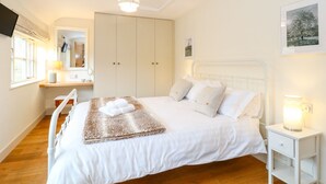 Une chambre à coucher comprenant un lit, une table de chevet, une commode, une armoire et un miroir.
