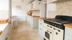 A kitchen with white cabinets, a black stove, and a tiled backsplash. - Greenham Cottage (Stoke-sub-Hamdon)