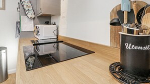 A kitchen with a microwave, toaster, and utensils holder. - Chapel Cottage (Filey)