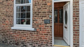 A brick building with a white window and a door. A sign on the wall reads "Chapel Cottage." - Chapel Cottage (Filey)