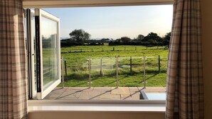 A room with a large window overlooking a grassy field. - Rhos Y Foel Cottage (Pwllheli)