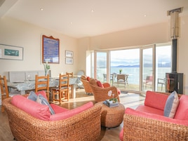 A spacious living area with wicker furniture, a dining table, and a view of the sea.