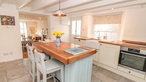 A modern kitchen with a wooden island, white cabinetry, and a built-in oven. - Rosevine (Kingsbridge)