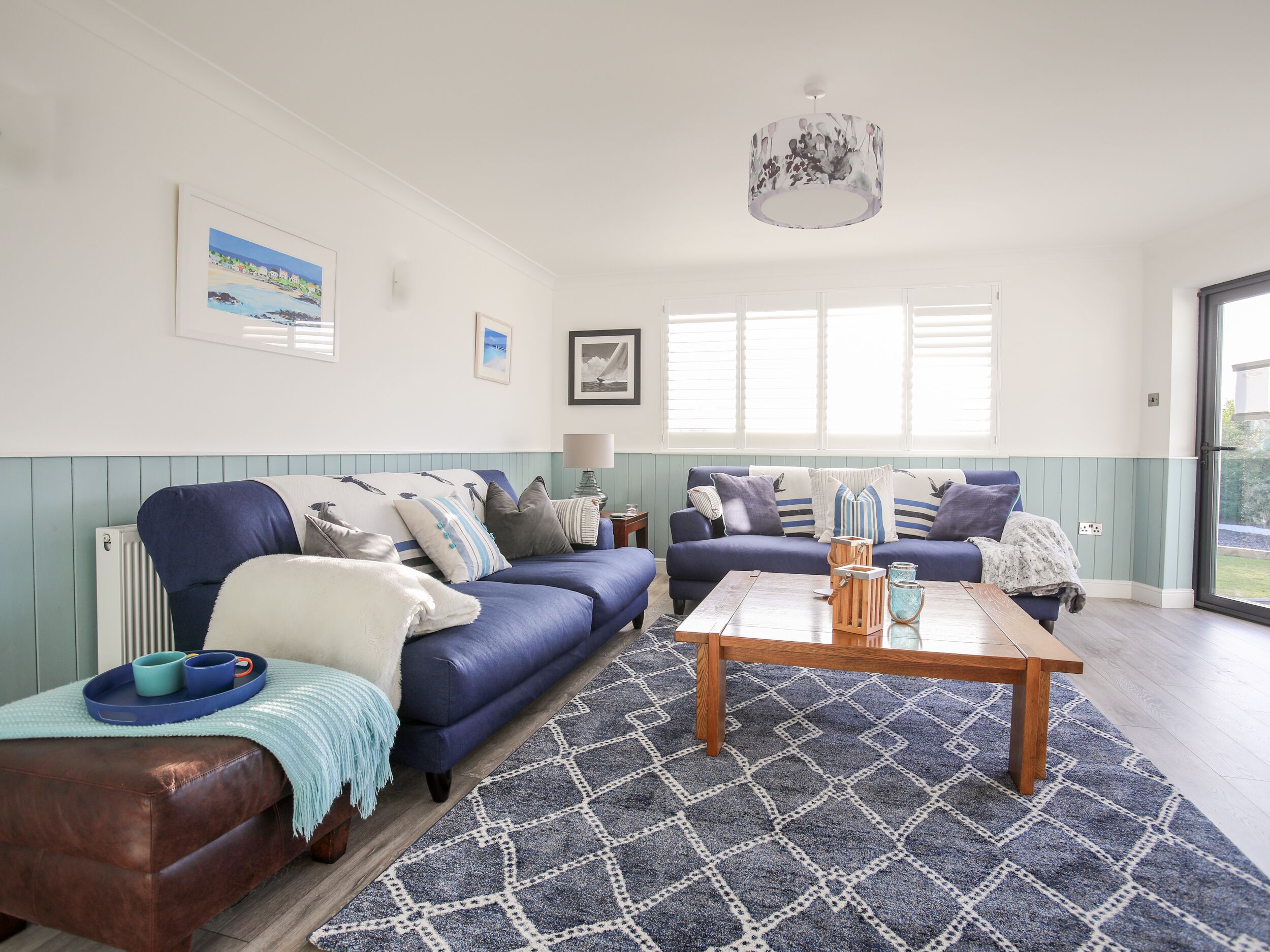 A cozy living room with two blue sofas, a wooden coffee table, and a patterned rug.