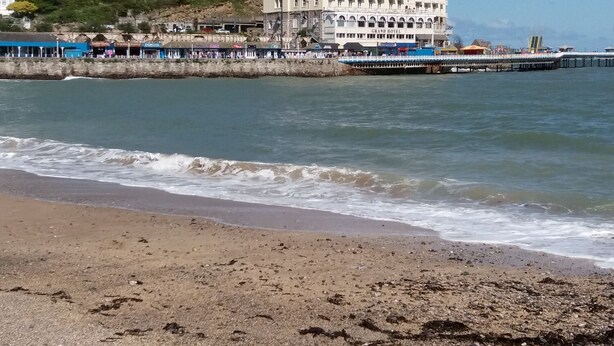 A coastal hotel with a prominent building, a pier extending into the water, and a beach in the foreground. - Beaulieu House (Llandudno)