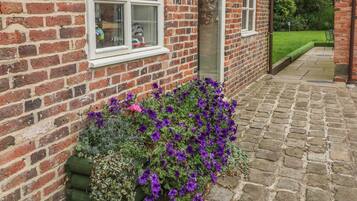 Traditional brick building with a charming garden featuring a variety of plants and flowers.
