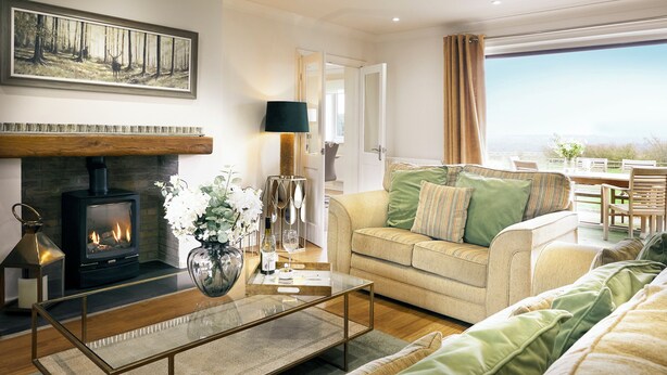 Ein Wohnzimmer mit Kamin, Sofa und Essbereich mit Blick.