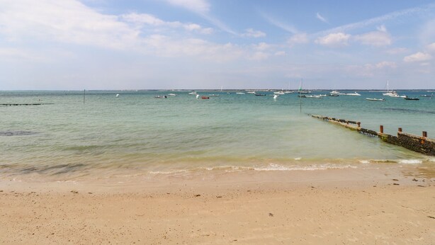 Una playa con vista despejada al mar y barcos.