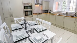 Una cocina moderna con armarios blancos, horno empotrado, microondas y estufa a gas.