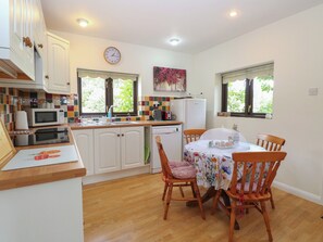 A compact kitchen with white cabinets, a microwave, a sink, and a dining area with a table and chairs.