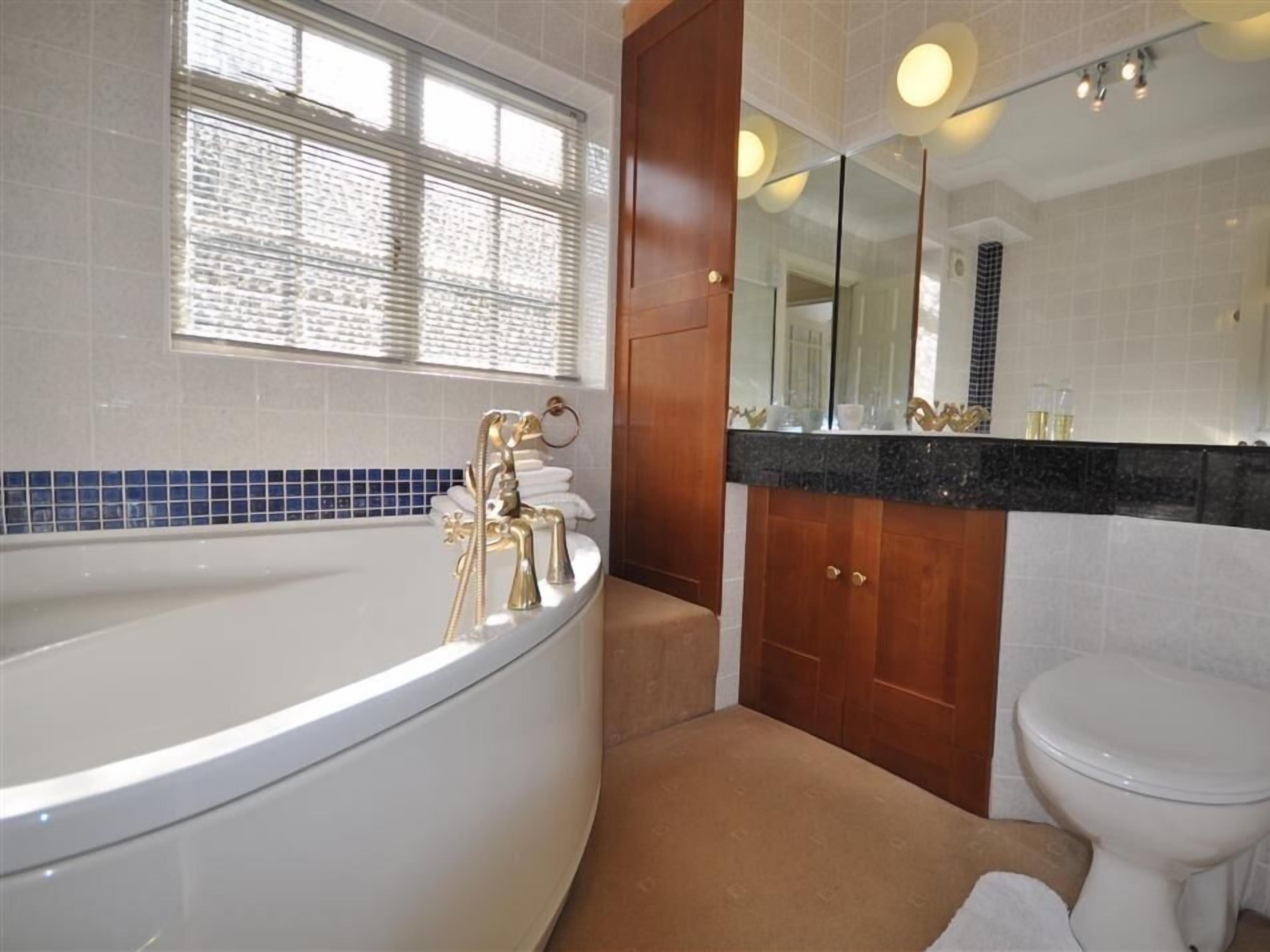 A modern bathroom with a freestanding bathtub, a large mirror, and a toilet.