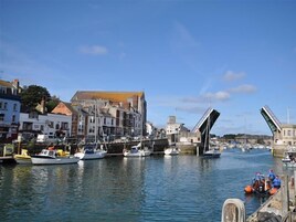 Un puerto con barcos amarrados, un puente y edificios a lo largo de la costa.