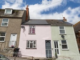 Un edificio de dos pisos con fachada rosa y verde, múltiples ventanas y antenas satelitales.