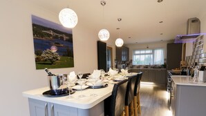 A modern kitchen with a central island, bar stools, and pendant lighting. - Gwelfor (Cemaes Bay)