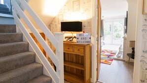 A staircase leading to a room with a wooden desk, a sign saying "HELLO AND WELCOME", and a television mounted on the wall. - Gwelfor (Cemaes Bay)