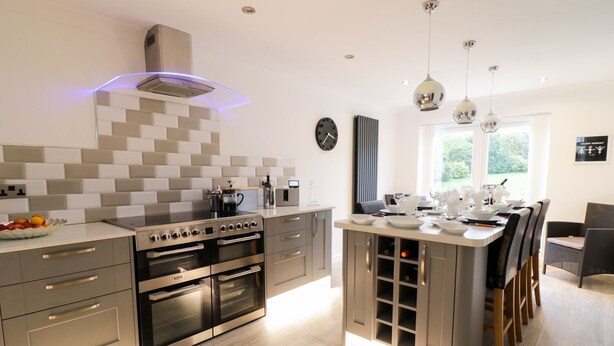 A modern kitchen with a central island, stainless steel appliances, and pendant lighting. - Gwelfor (Cemaes Bay)