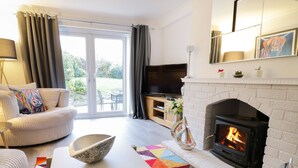 A modern living room with a fireplace, sofa, and TV. - Gwelfor (Cemaes Bay)