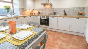 Une cuisine compacte avec des meubles blancs, un four encastré et une fenêtre offrant une belle vue.