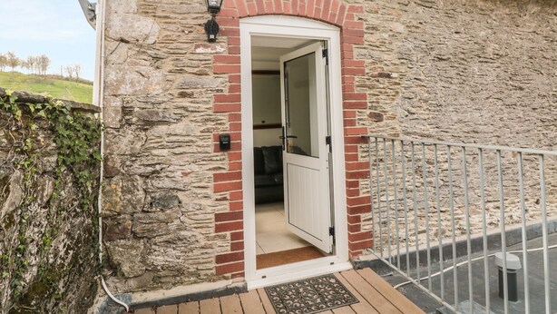 Ein Steinhaus mit einer weißen Tür und einer kleinen Veranda.