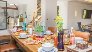 Ein Esstisch, reichhaltig gedeckt mit Speisen, Getränken und einer Blumenvase.