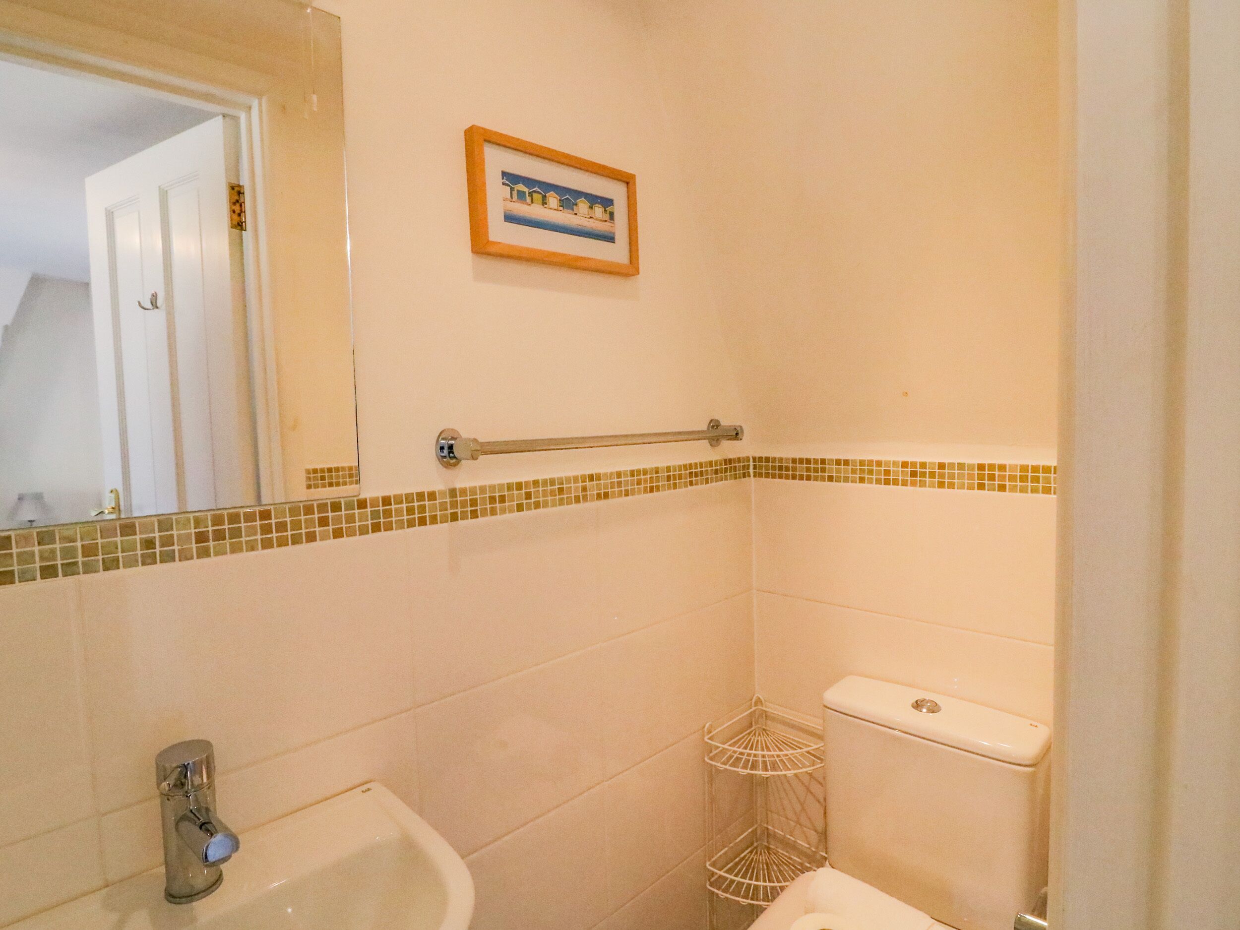 A bathroom with a white sink, a toilet, a towel rack, and a framed picture on the wall.