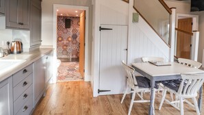 A kitchen with grey cabinets, a coffee maker, and a dining area with a table and chairs. - The Stables (Scarborough)
