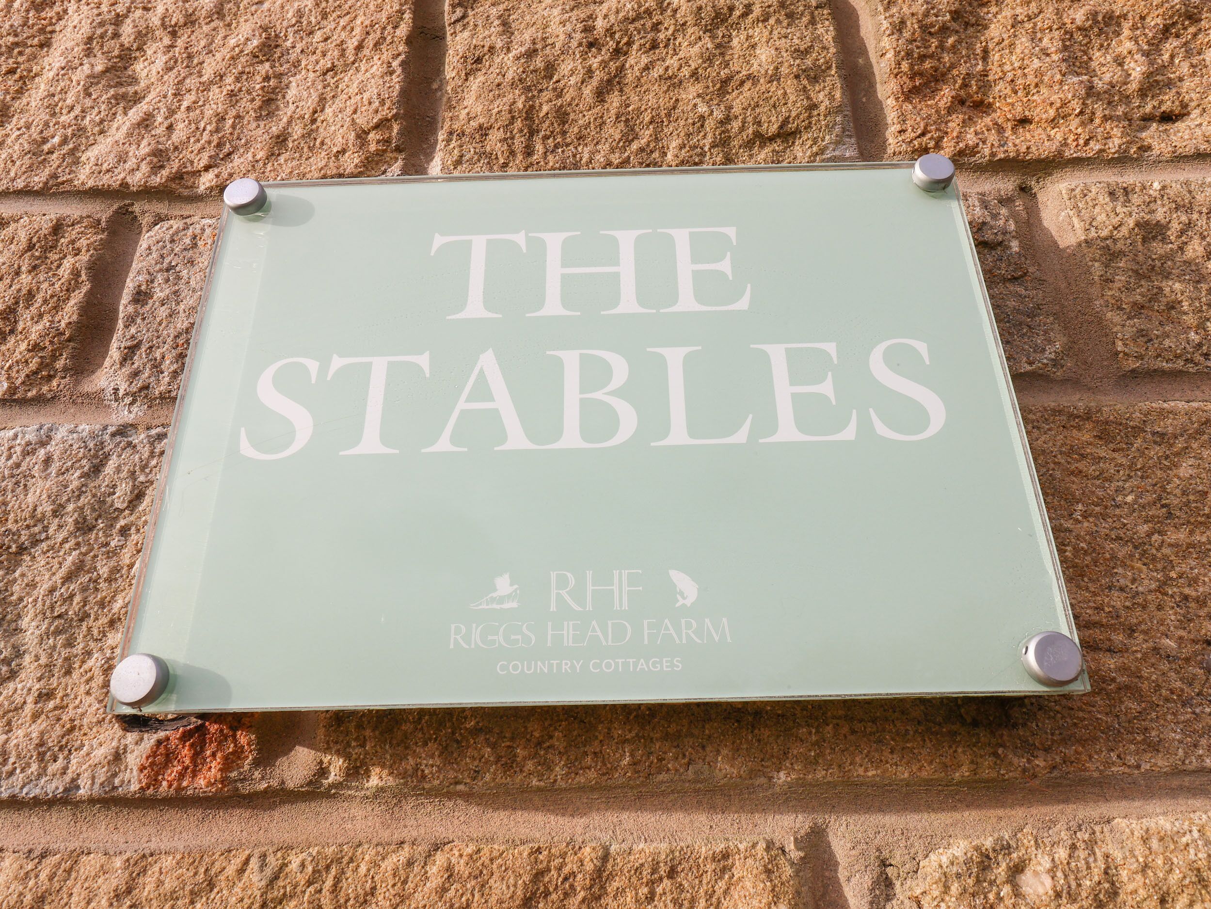 Une enseigne indiquant « The Stables » à la ferme de Riggs Head, qui propose des locations de cottages à la campagne.