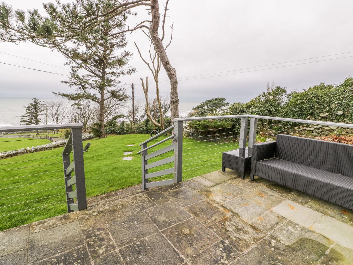 A stone staircase leading to a grassy area with a bench and a view of the sea.