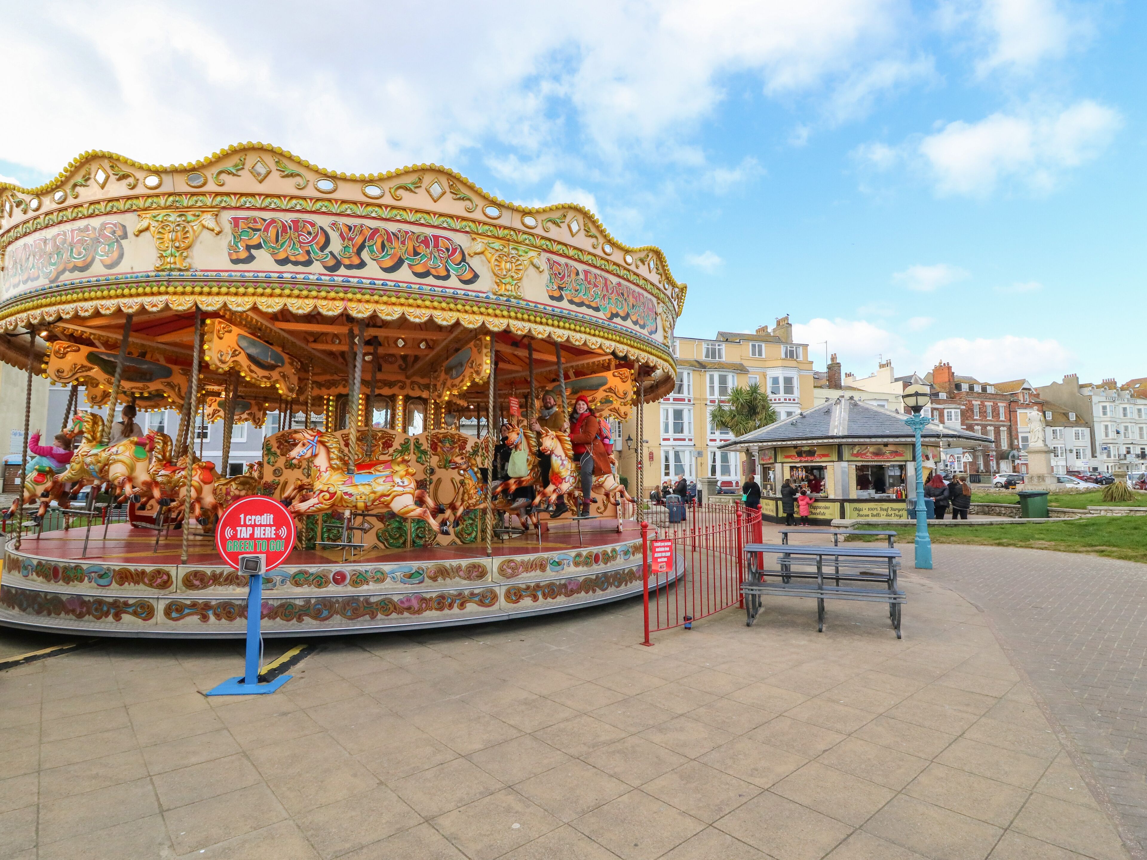 A carousel with colorful horses and a sign that reads "FOR YOUR".