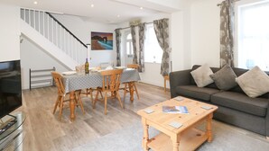 Un vaste espace de vie comprenant une table à manger pour quatre personnes, un canapé, une table basse et un téléviseur.