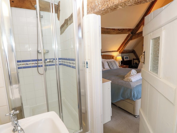 Ein Badezimmer mit Dusche, Waschbecken und einem Bett mit blauer Decke und Handtuch.