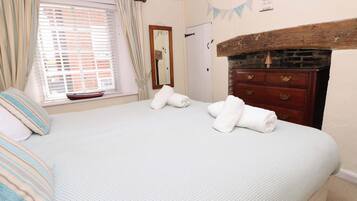 Un dormitorio con cama, cómoda, espejo y ventana con cortinas.