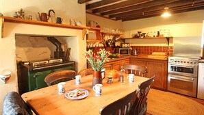 Una cucina accogliente con un tavolo di legno, sedie e diversi elettrodomestici, tra cui fornello, forno a microonde e forno.