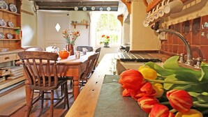 Una cucina rustica con mobili in legno, un lungo tavolo di legno e diversi utensili da cucina appesi al muro.