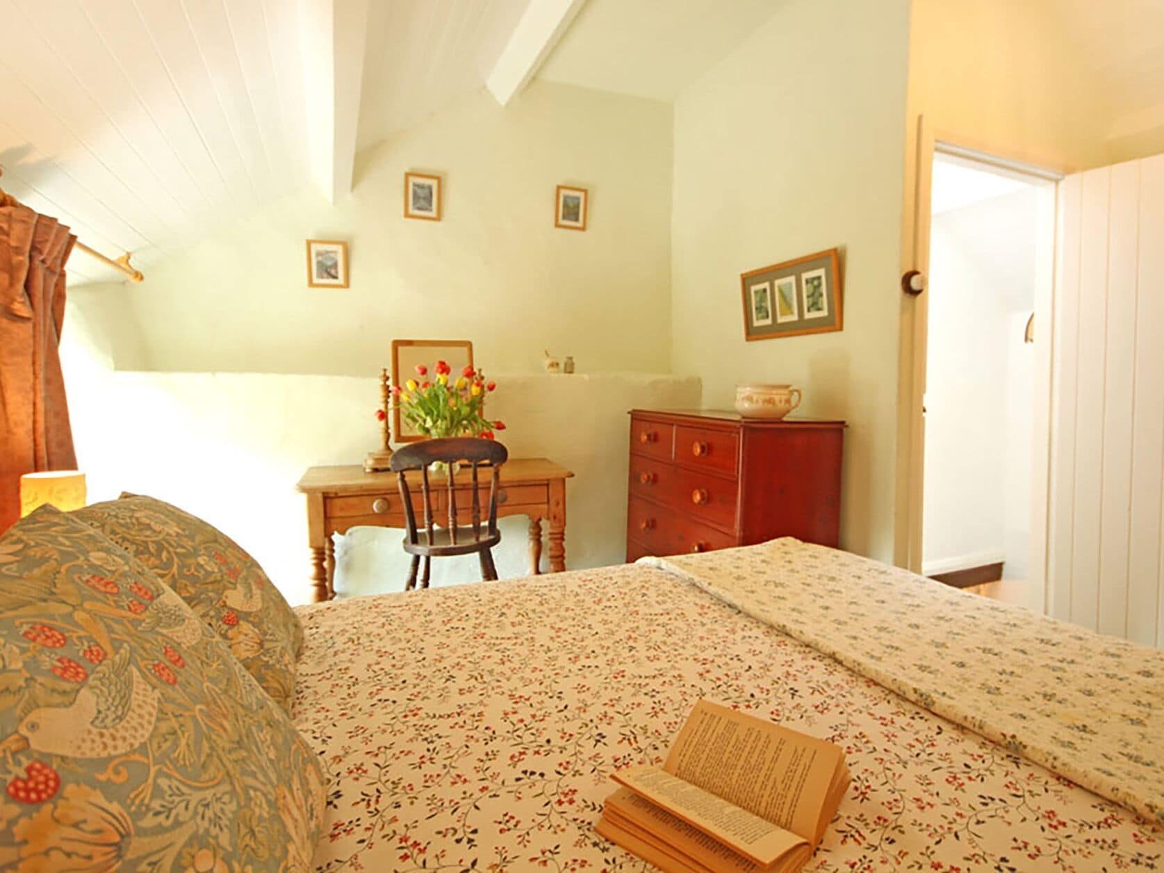 Une chambre à coucher avec un lit, un bureau, une chaise, une commode et une porte.