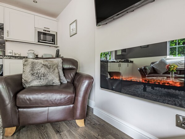 A modern living room with a leather sofa, a large mirror, and a kitchen in the background.