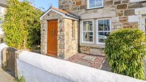 A stone house with a wooden door, a small porch, and a window. - Miner's Rest (Camborne)