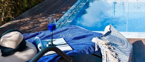 Una piscina al aire libre, sillones reclinables de piscina
