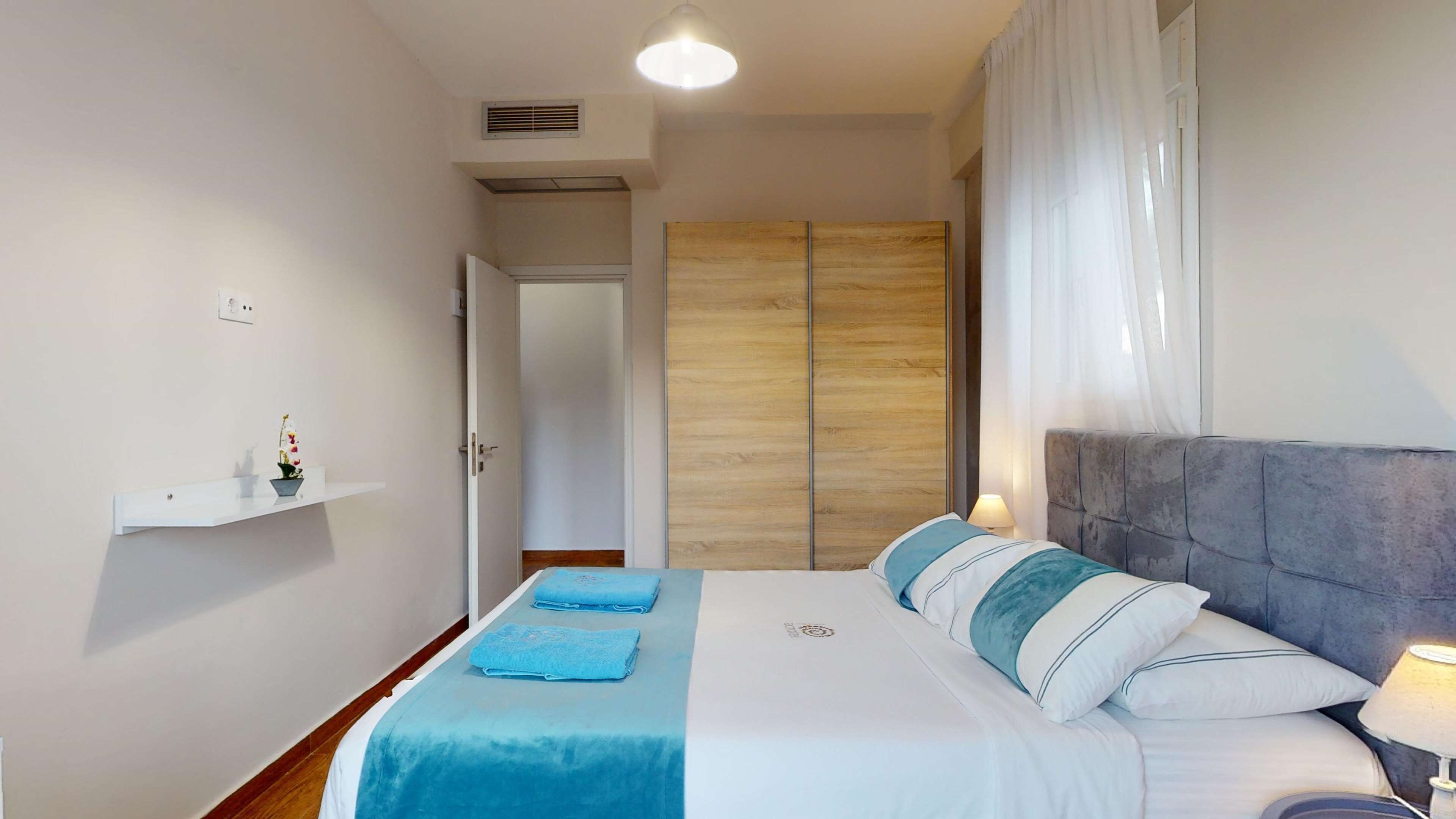 Une chambre à coucher comprenant un lit, une table de chevet, une commode, une armoire et une étagère avec une plante.