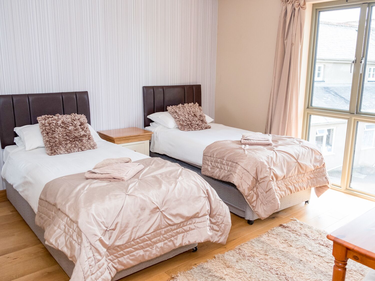 Habitación de hotel con dos camas, un ventanal grande y vistas al exterior.
