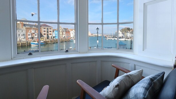 A bay window with a view of a marina and buildings. - Tradewinds (Weymouth)